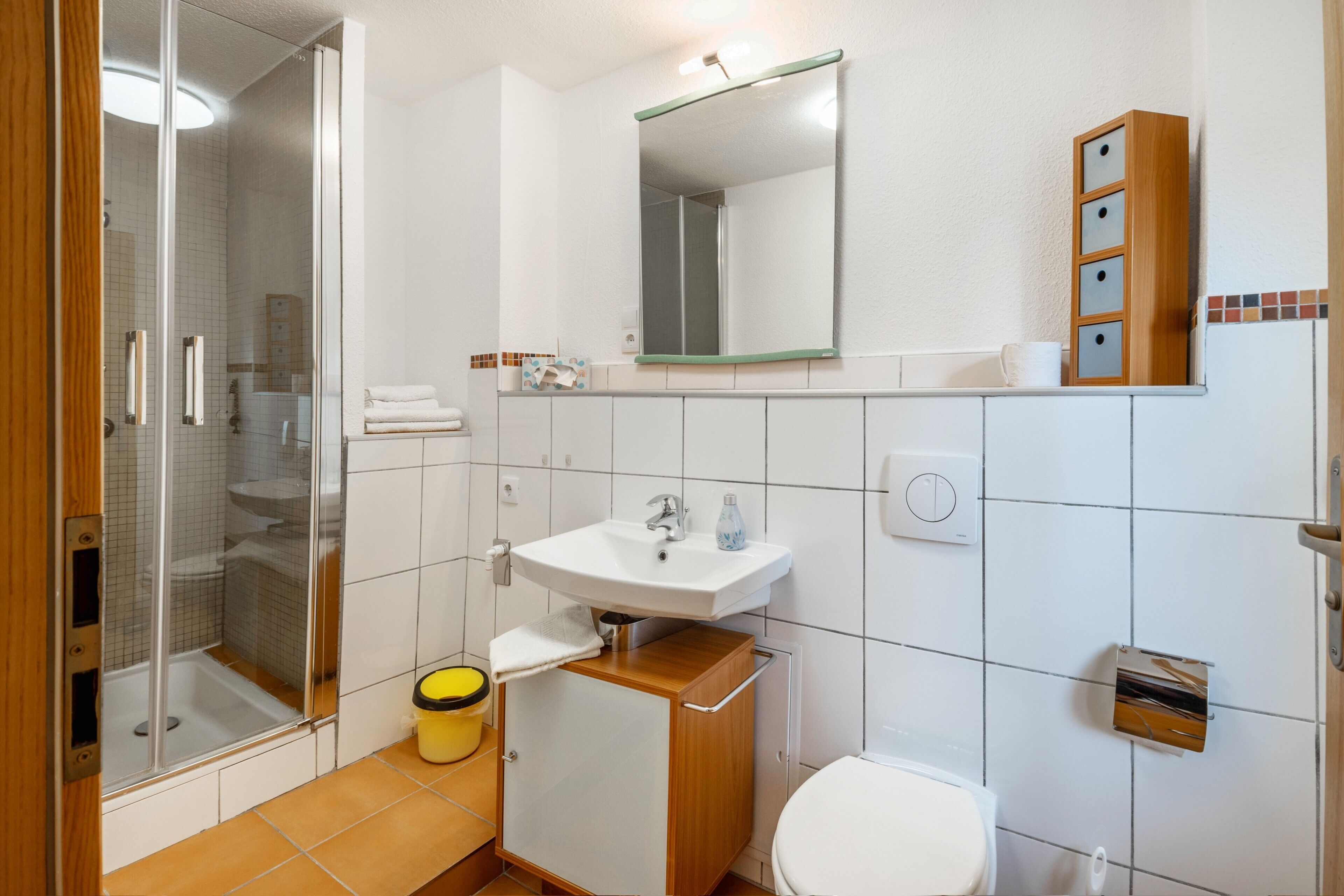A bathroom with a shower, sink, toilet, and a mirror.