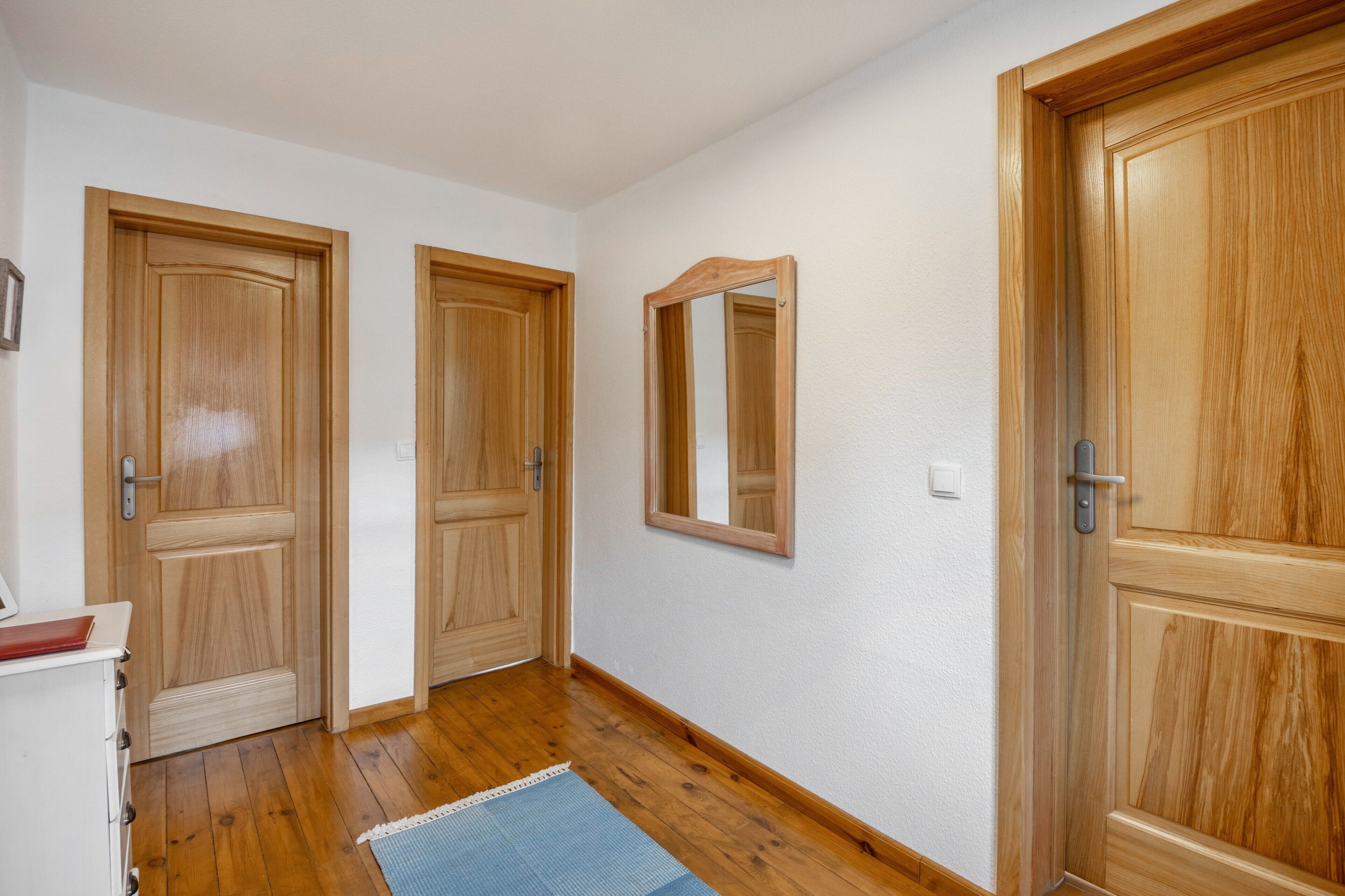 A hallway with wooden doors, a mirror, and a white wall.