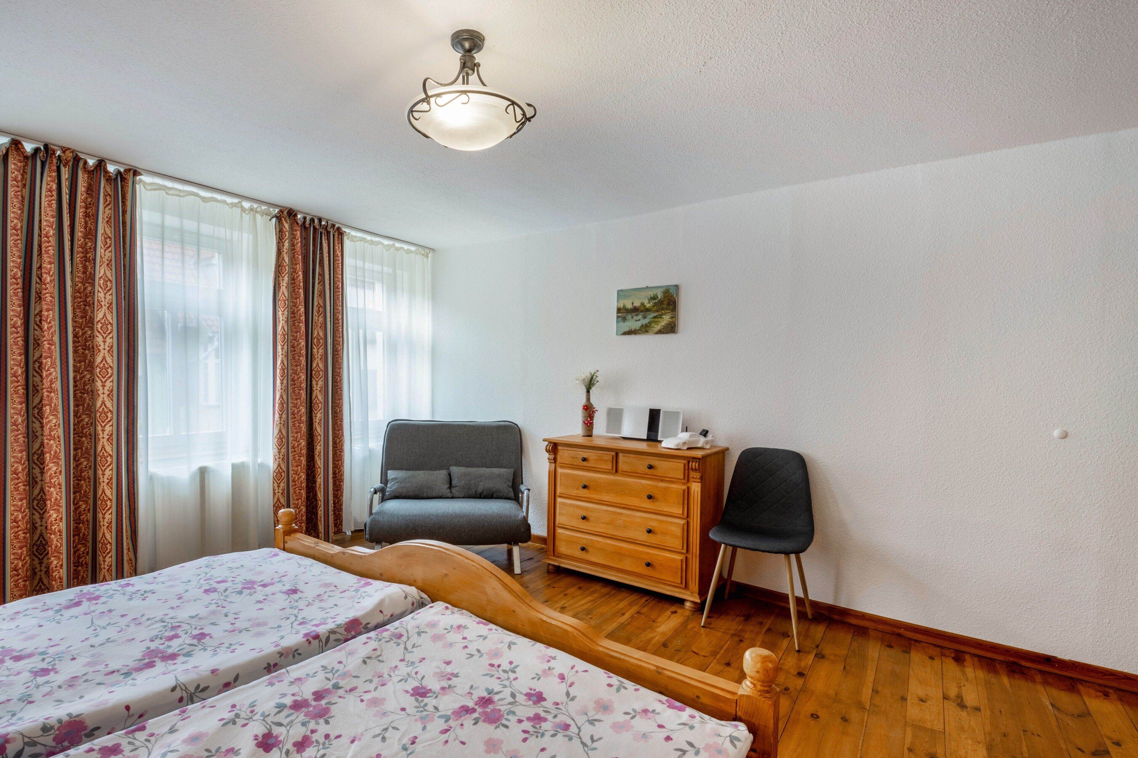 Ein Schlafzimmer mit zwei Betten, einem Schminktisch, einem Stuhl und einer Deckenleuchte.