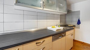 A kitchen with a black countertop, white cabinets, a dishwasher, and a blue towel hanging on the wall. - Holiday Apartment "Kolibri" with Shared Terrace & Shared Garden (Naumburg (Saale))