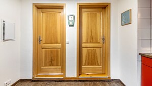 A hallway with two wooden doors, a wall-mounted clock, and a framed picture.