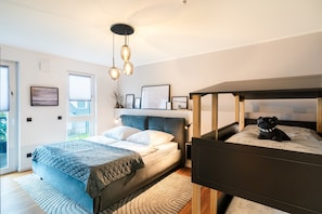 A bedroom with a bed, a bunk bed, a window, and a ceiling light fixture.