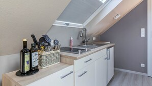 Eine Küche mit Dachfenster, Spüle und Arbeitsplatte mit Flaschen und Geschirr.