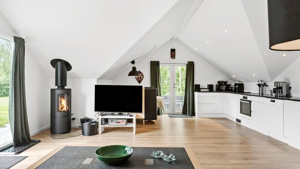 Un loft spacieux doté d’une cuisine moderne, d’une cheminée et d’un grand téléviseur dans l’espace de vie.