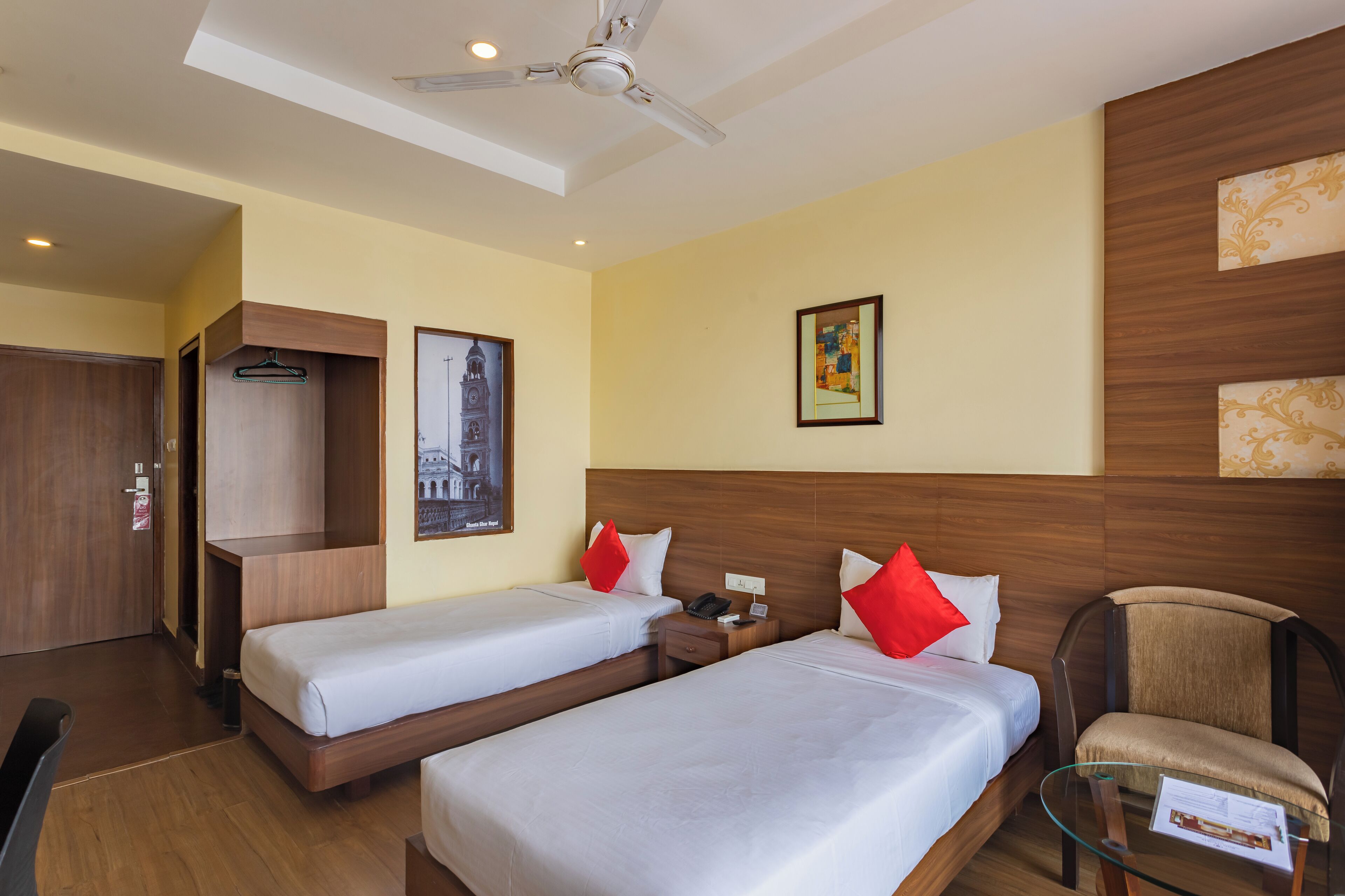 Habitación de hotel con dos camas, una silla, un escritorio, un armario y un ventilador de techo.