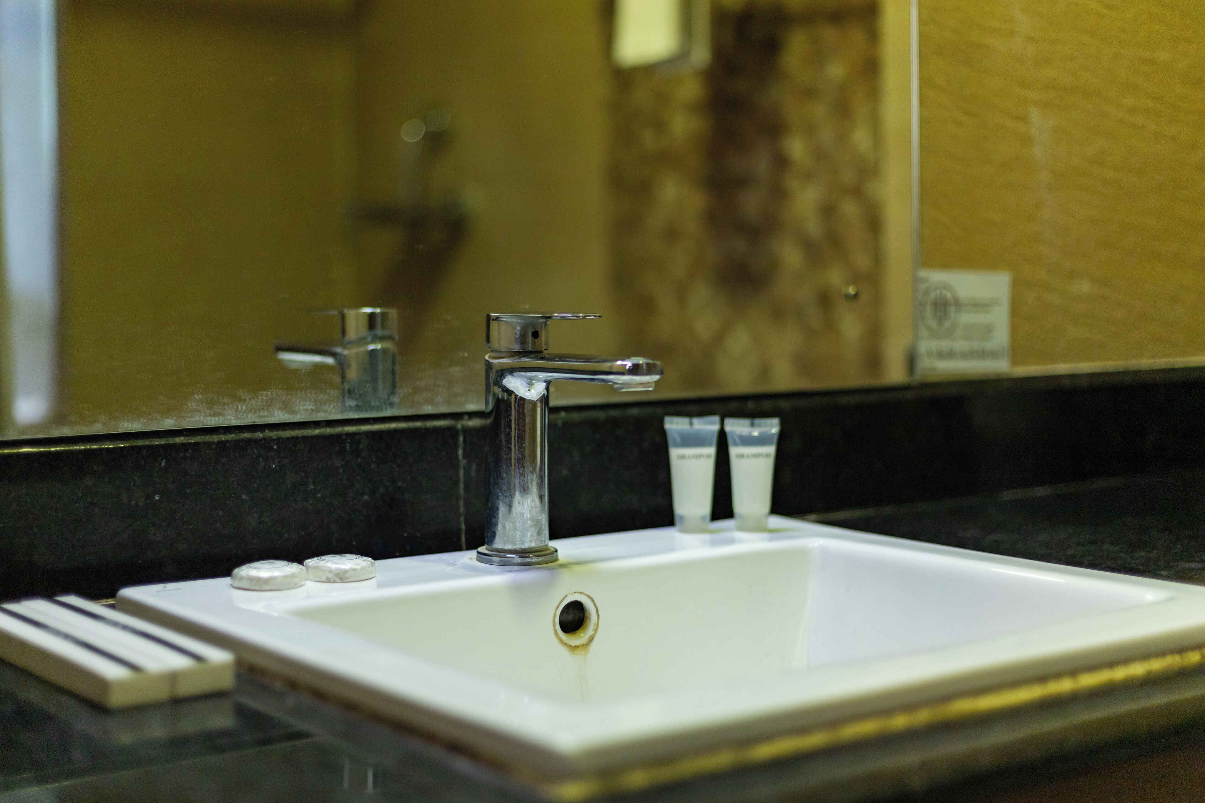 A bathroom sink with a mirror, a faucet, and two small containers on the countertop.