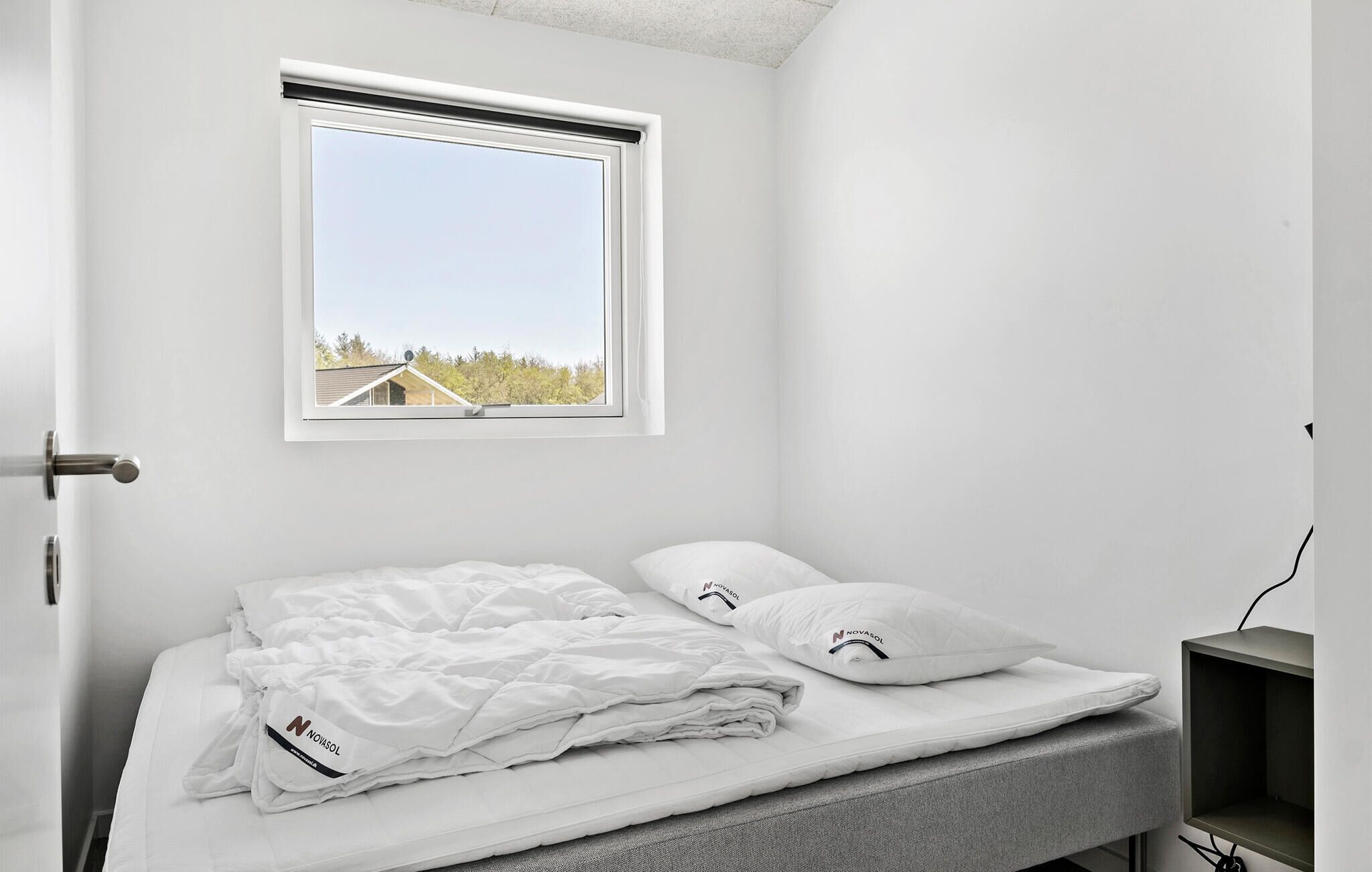A bedroom with a bed, pillows, a window, and a desk.