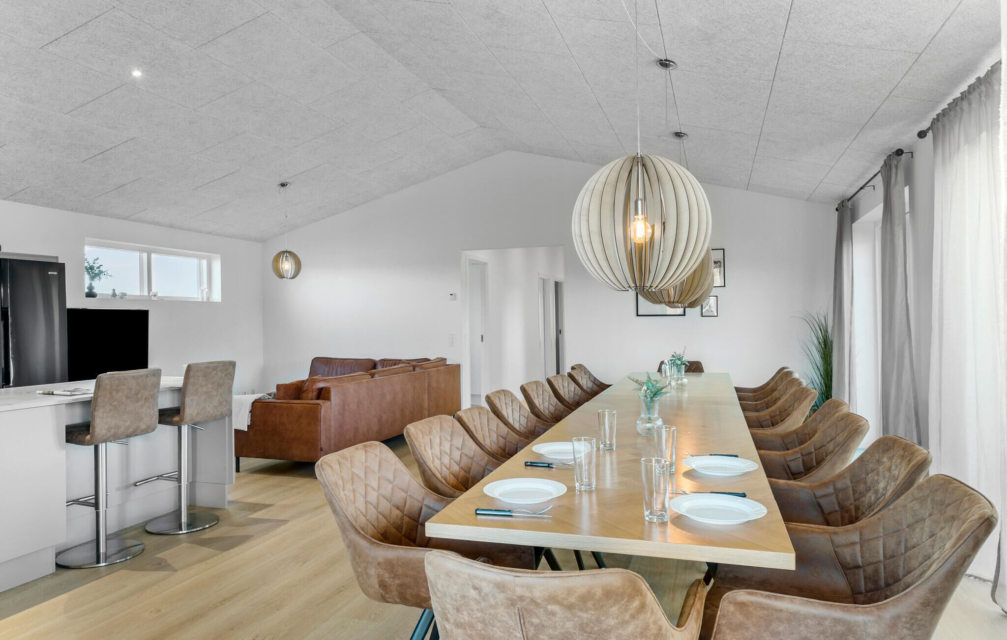Un espace de restauration moderne, doté d’une longue table, de chaises confortables et d’un luminaire suspendu original.
