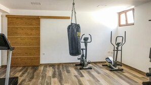 Kotikuntosali, jossa on kuntopyörä, spinningpyörä ja nyrkkeilysäkki.