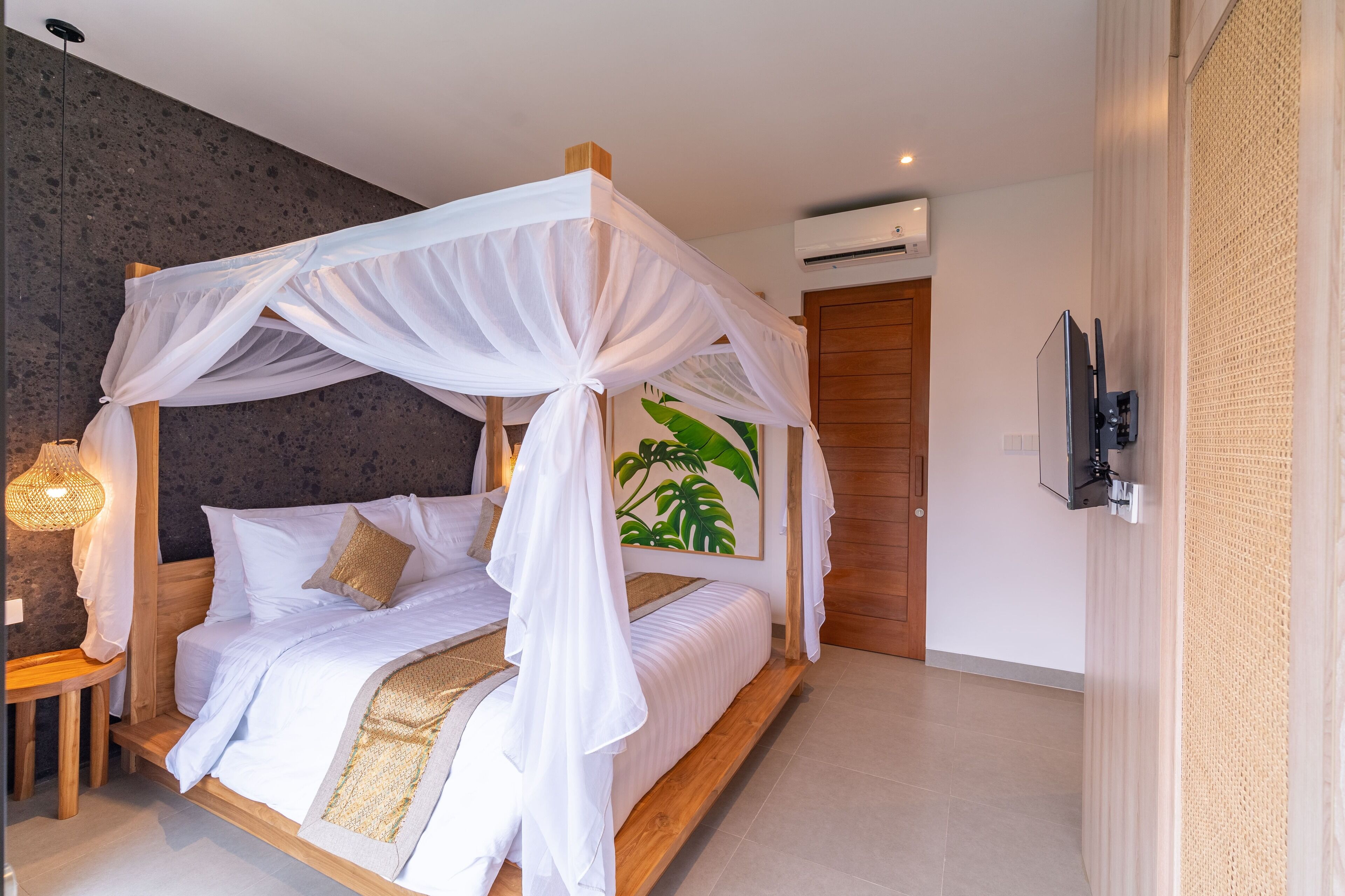 Ein Schlafzimmer mit Baldachinbett, Holz-Kopfteil, Wand-Fernseher und einem großen Pflanzenbild.