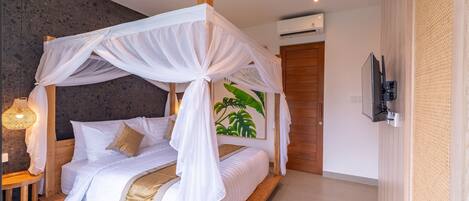 Ein Schlafzimmer mit Baldachinbett, Holz-Kopfteil, Wand-Fernseher und einem großen Pflanzenbild.