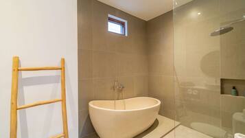 Un bagno moderno con una vasca da bagno indipendente, un box doccia in vetro e una piccola finestra.