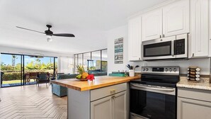 A modern kitchen with a wooden countertop, stainless steel appliances, and a view of the outdoors. - Keauhou Punahele E103, w/AC (Kailua Kona)