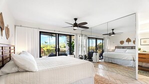 A bedroom with a large bed, a ceiling fan, a sofa, and a view of the outdoors. - Keauhou Punahele E103, w/AC (Kailua Kona)