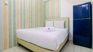 A room with a bed, a blue refrigerator, and striped wallpaper. - OYO LIFE ROOMS BY MIXO  (Jakarta)