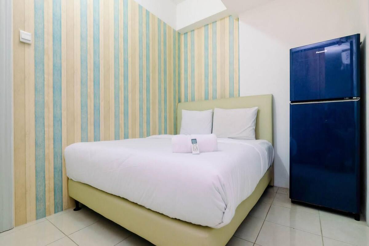 Een kamer met een bed, een blauwe koelkast en gestreept behang.