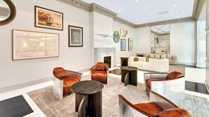 Uma sala de estar ampla, com lareira, móveis modernos e obras de arte nas paredes.