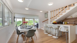 Une cuisine moderne dotée d’un îlot central, de planchers en bois et d’un escalier menant à un niveau supérieur.