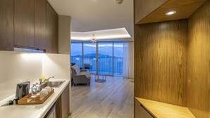 A modern kitchen with a wooden countertop, a dining area with a sofa, and a balcony with a view.