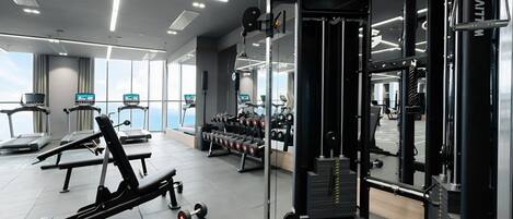 Een moderne sportschool met loopbanden, gewichtbanken en diverse fitnessapparaten.