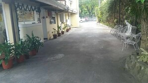 A narrow alley with potted plants on the left and outdoor seating on the right. - REGENCY PLAZA TOURIST INN (Bacolod)