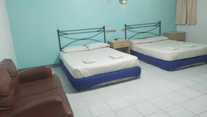 A room with two beds, a brown chair, and a small bedside table with a lamp. - REGENCY PLAZA TOURIST INN (Bacolod)