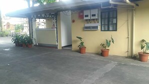 A building with a covered entrance, potted plants, and a window with a view. - REGENCY PLAZA TOURIST INN (Bacolod)