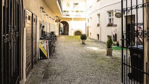 Un estrecho callejón empedrado flanqueado por edificios, con una bicicleta estacionada cerca de la entrada y un letrero que dice 'Brico'.