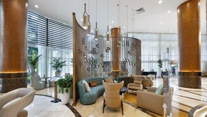 A spacious lobby with a curved seating area, a piano, and a large plant.