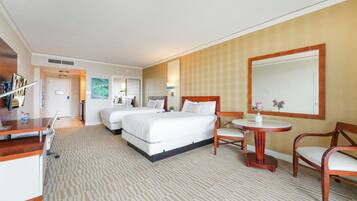 A hotel room with two beds, a desk, a chair, a small table, and a large mirror.
