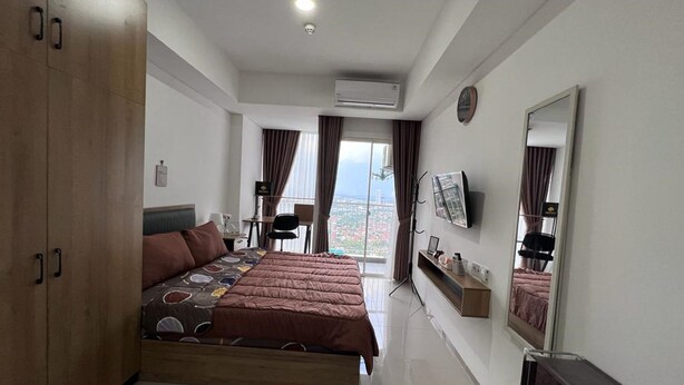 Quarto de hotel moderno com cama grande, escrivaninha, cadeira, TV e vista para a cidade.