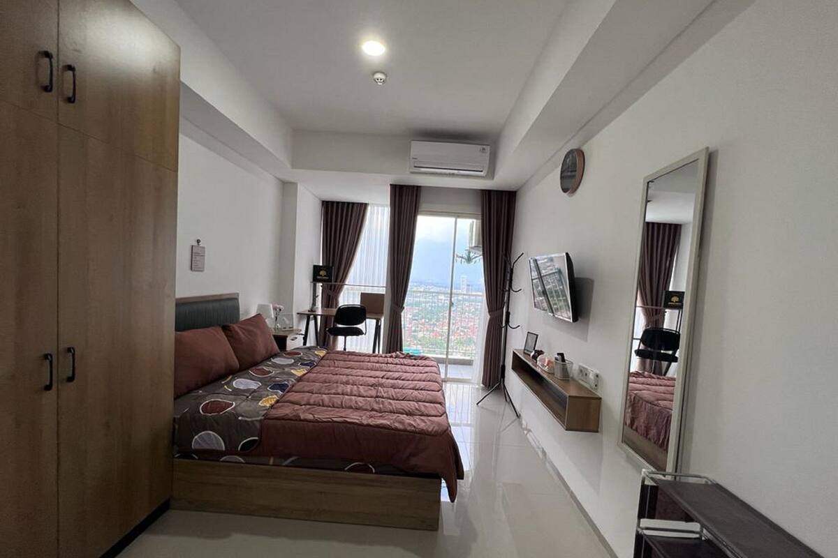 Een moderne hotelkamer met een groot bed, een bureau, een stoel, een televisie en uitzicht op de stad.