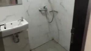 Um banheiro com pia branca, espelho e chuveiro com chuveiro manual.