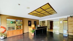 Uma área de recepção moderna com balcão de vidro, armários de madeira e piso ladrilhado.