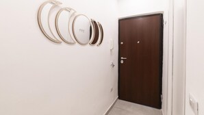 A hallway with a wooden door and wall-mounted mirrors. - Vico Cangiani al Mercato 20 (Naples)