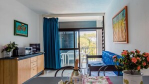 Una habitación con mesa de comedor para dos personas, kitchenette, sofá y balcón con vistas.