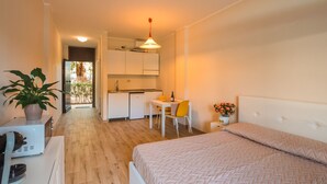 A compact bedroom with a bed, a small desk, and a kitchenette. - Mono Garden by Interhome (Marina di Bibbona)