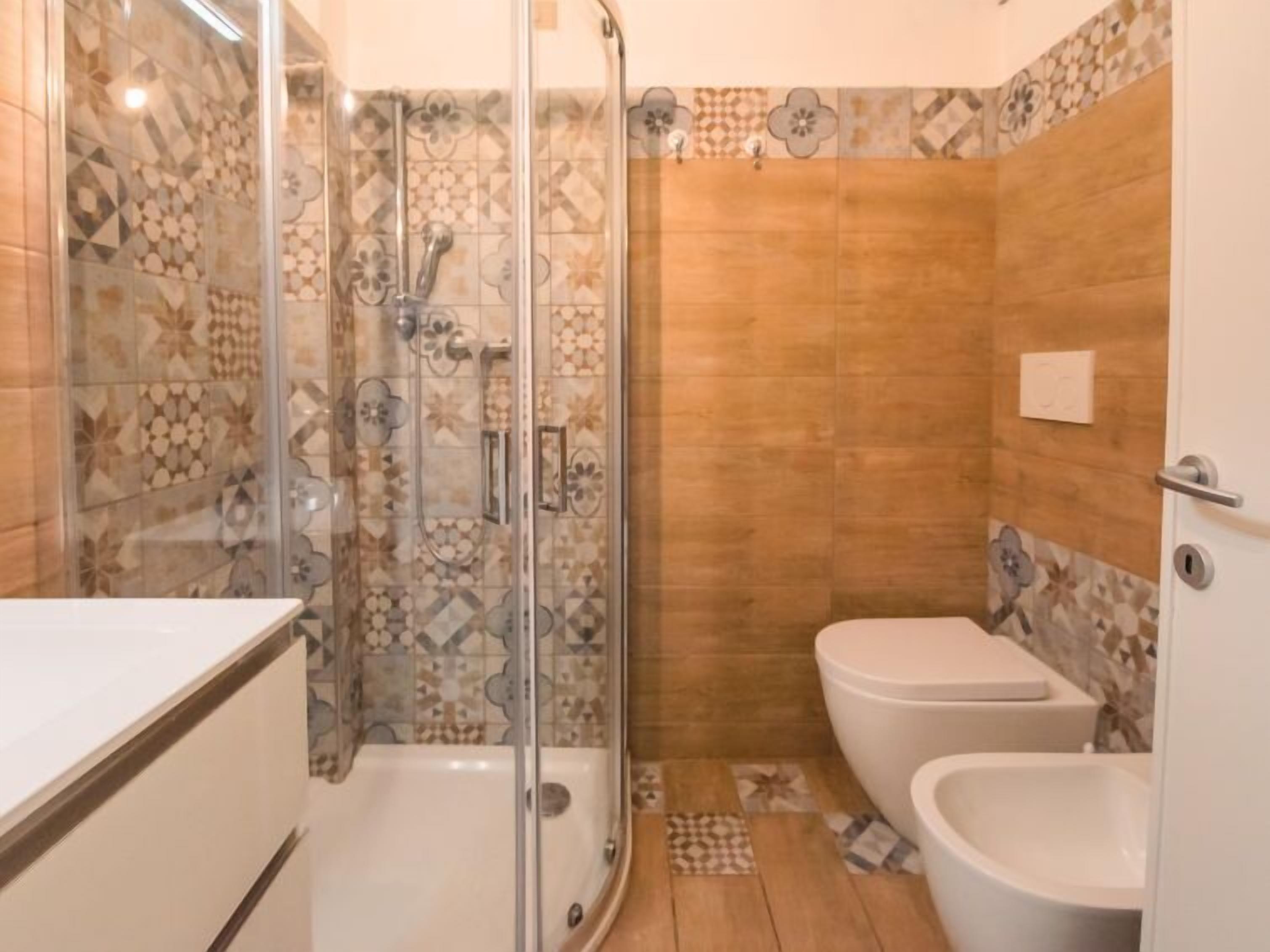 A bathroom with a glass-enclosed shower, a toilet, and a bidet.