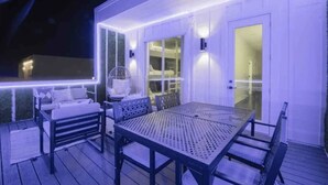 En udendørs terrasse med et bord, stole, en sofa og en ventilator.