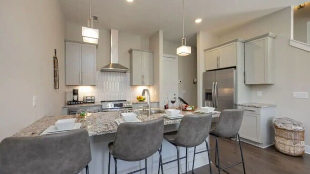 A modern kitchen with a central island, bar stools, and built-in cabinets. - Luxury Home w/ Rooftop & 8 Beds! 10 to Downtown! (Nashville)