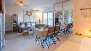 Un salon moderne avec un canapé, une table à manger et des chaises. On y trouve également une bibliothèque, une lampe et un grand miroir.