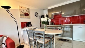 A modern kitchen with red tiles, stainless steel appliances, and a dining area with a round table and chairs.