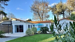 A modern house with a well-maintained lawn, a patio with a blue umbrella, and a garage.