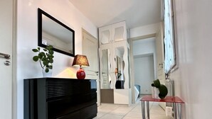 A modern hallway with a black console table, a red lamp, and a mirror on the wall.