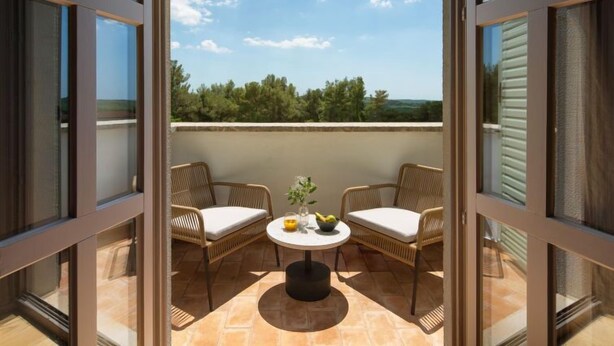 A balcony with wicker chairs and a round table, overlooking a scenic landscape. - Rorripa by Interhome (Poreč/Sv. Lovreč)