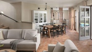 A spacious living area with a sofa, a dining table with chairs, and a kitchen area with cabinets and a brick column. - Calluna by Interhome (Poreč/Sv. Lovreč)