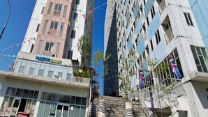 A tall building with multiple floors, a staircase leading to the entrance, and a sign indicating a business or office space. - OYO Life 93140 Apartment Grand Sentraland By Fahri (Karawang)