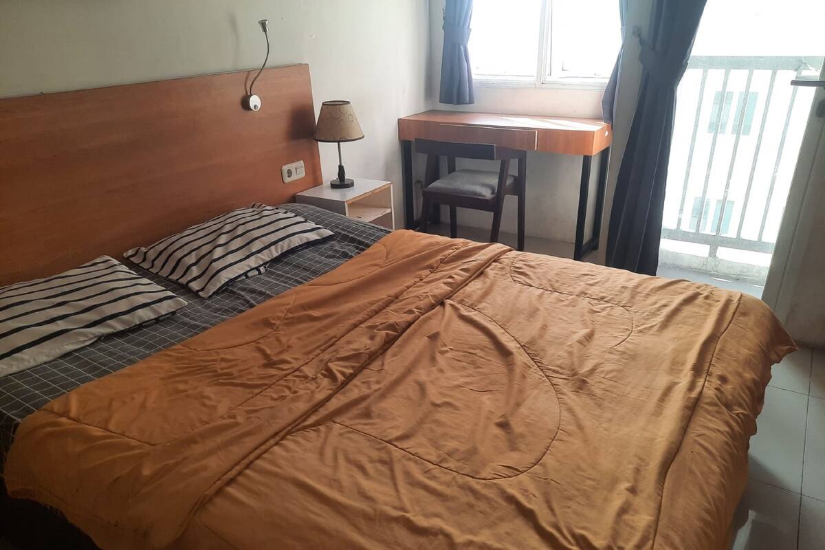 A bedroom with a bed, a desk, and a chair.