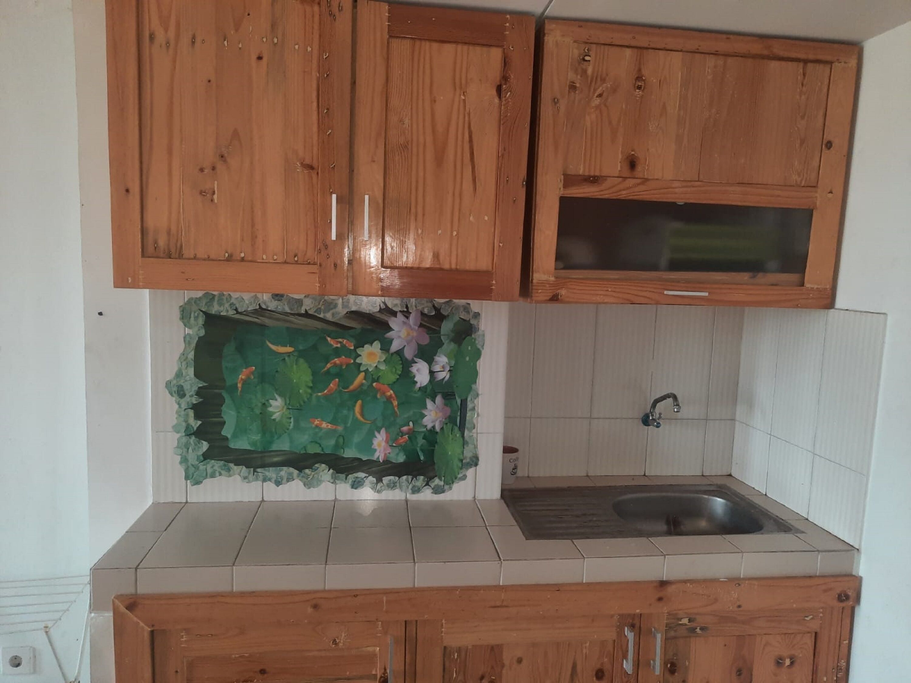 A kitchen with wooden cabinets, a tiled backsplash, and a sink.