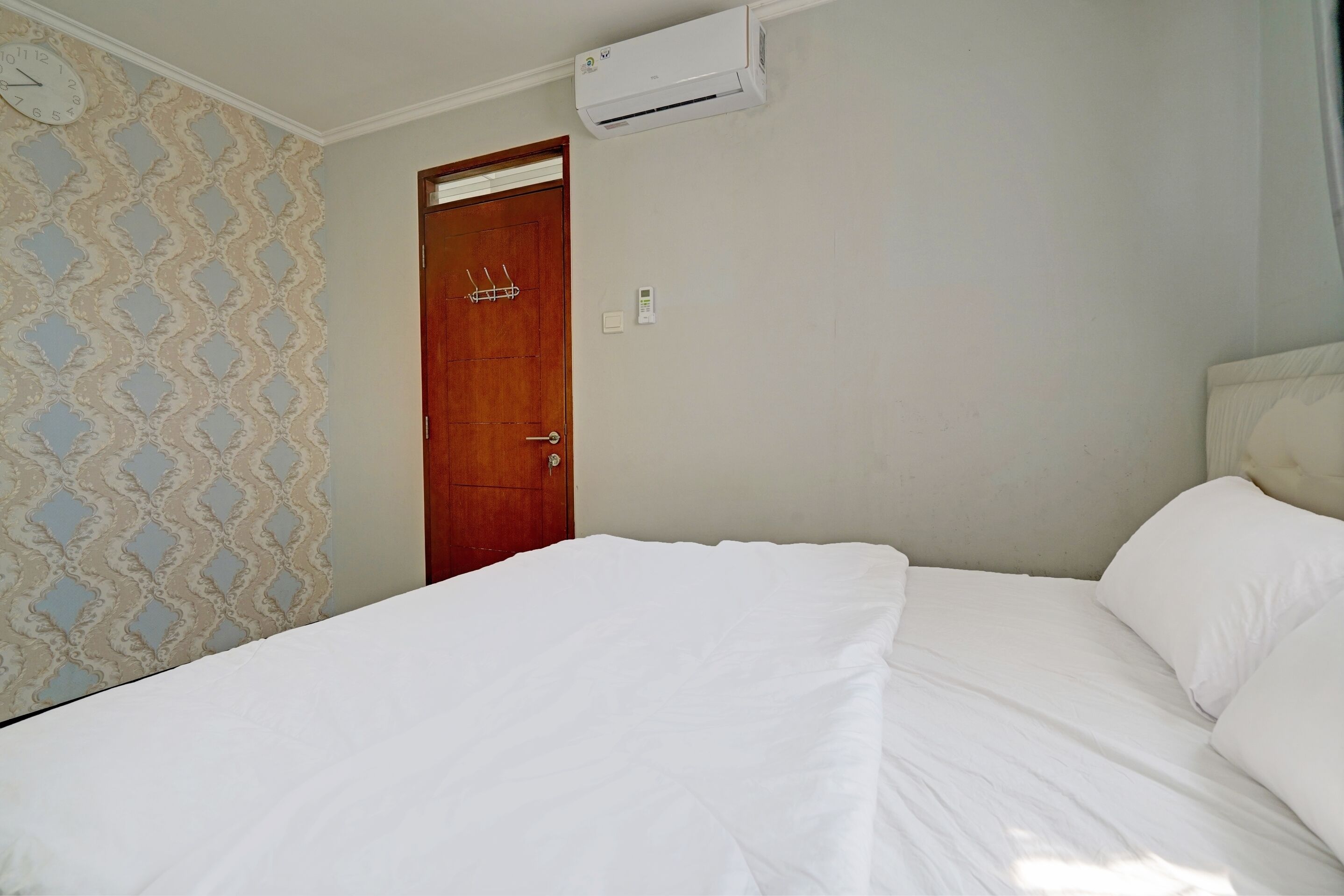 Une chambre avec un lit, une porte en bois et un appareil de climatisation fixé au mur.